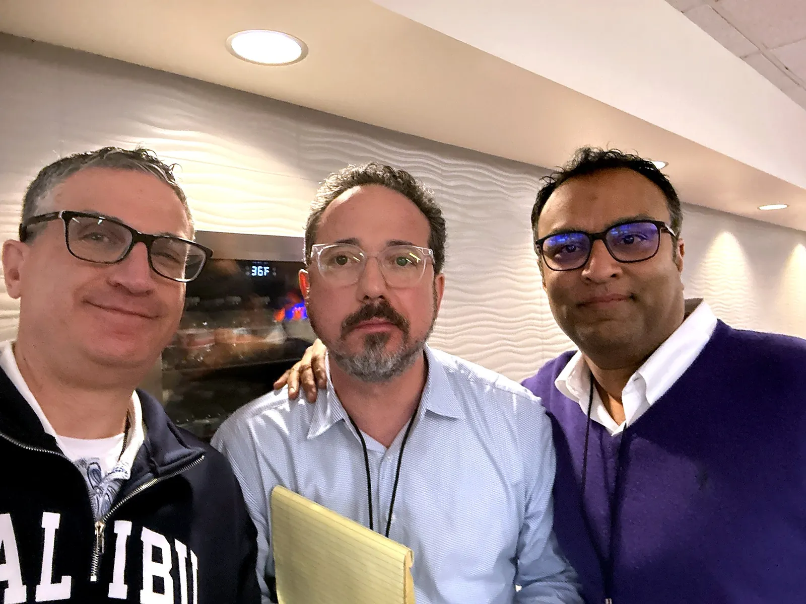 Andrew J. Hillman in an indoor selfie with two men, one holding a legal pad