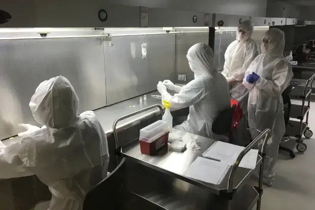 Compound pharmacy cleanroom with USP 797 garbed technicians, vertical laminar flow hood, IV preparation
