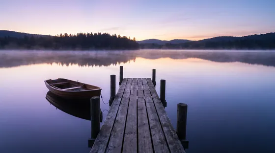 Wooden dock and rowboat on a still lake at dawn, illustrating moments on Andrew Hillman's record